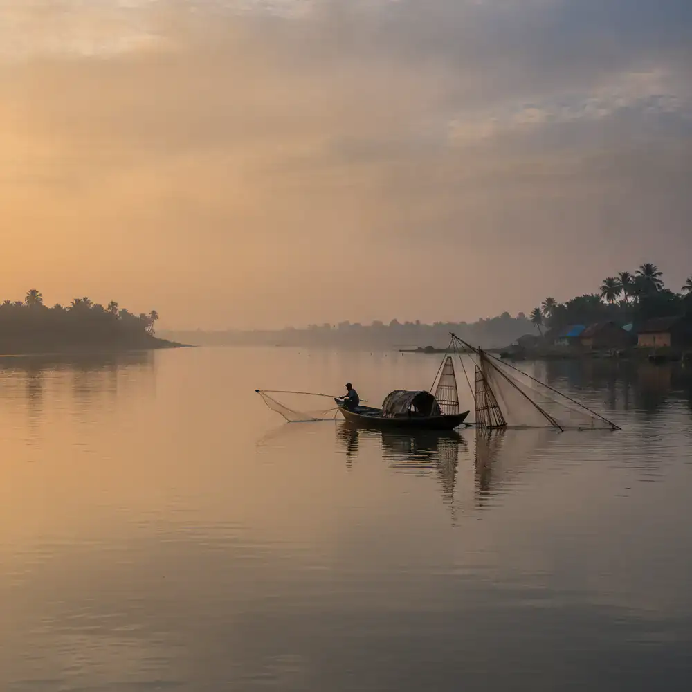 Calm river in Bangladesh at dawn with fishing gear silhouette